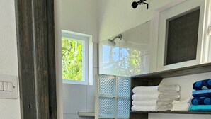 Ein kleines Badezimmer mit Toilette, einer Glasabtrennung und einem Handtuchregal.