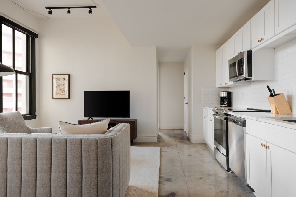 Una cocina moderna con armarios blancos, microondas integrado y cafetera.