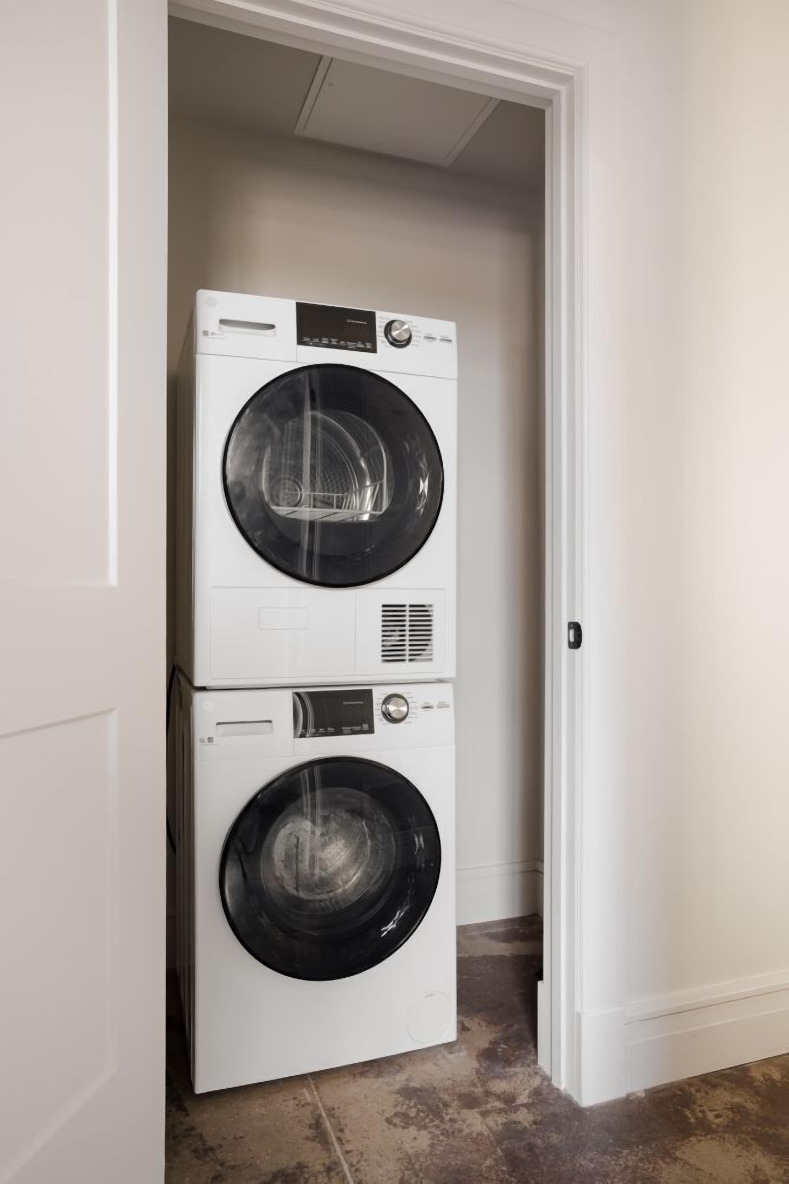 A stacked washer and dryer unit in a hallway.