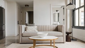 A modern living room with a beige sofa, a round wooden coffee table, and a white bowl on it.