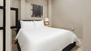 Un lit bien fait dans une chambre d’hôtel au design moderne, une table de chevet avec une lampe et une œuvre d’art accrochée au mur.