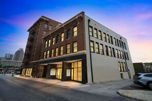 A multi-story building with a mix of brick and modern facade, featuring large windows and a ground-level entrance. - Historic Light, Modern Living at La Luz (San Antonio)