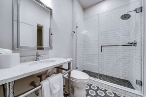 Une salle de bain moderne avec un meuble-lavabo blanc, un grand miroir, une douche en verre et des toilettes.