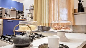 Une cuisine équipée d’une cuisinière à gaz, d’une bouilloire, d’une machine à café et d’un présentoir à pâtisseries.