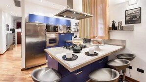 Une cuisine moderne dotée d’un îlot central, d’appareils électroménagers en acier inoxydable et de tabourets de bar.