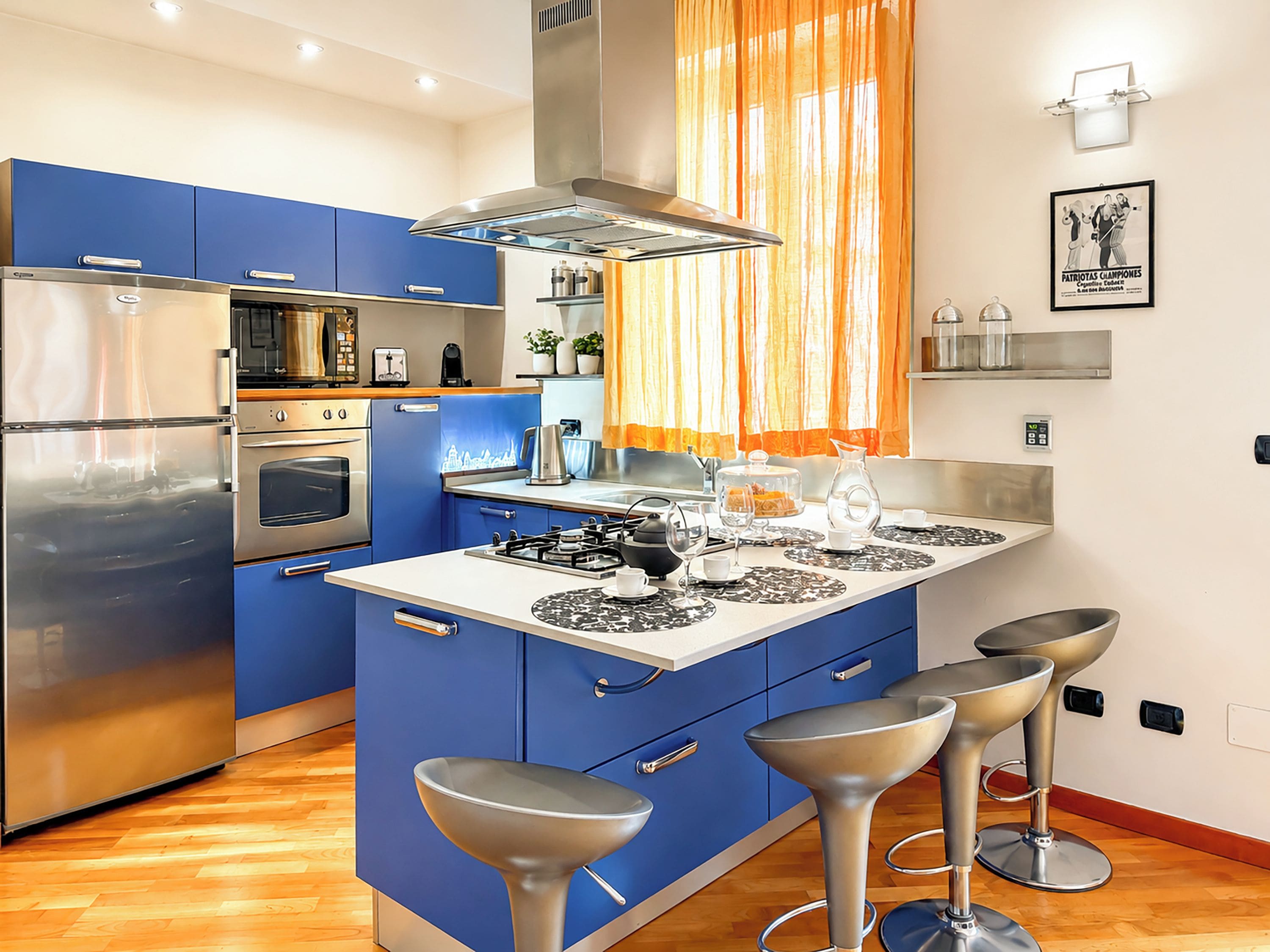 Une cuisine moderne avec des meubles bleus, des appareils en acier inoxydable et un îlot central doté de tabourets de bar.