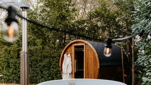 A wooden cabin with a hot tub, surrounded by greenery.