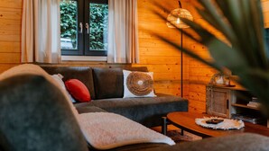 A cozy living room with a sofa, cushions, a small table, and a window with curtains.
