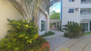 A courtyard with a pathway, surrounded by greenery and a building with multiple floors and balconies. - A 300 Mtos da Arena da Amazônia e Centro de Convenções Vasco Vasquez (Chapada)