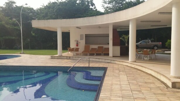 A swimming pool with a wavy design, surrounded by a covered seating area with chairs and a small kiosk. - A 300 Mtos da Arena da Amazônia e Centro de Convenções Vasco Vasquez (Chapada)