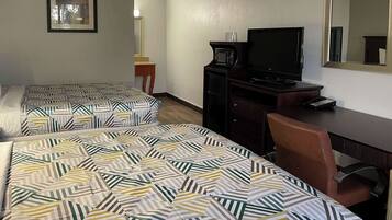 Habitación de hotel con dos camas, un escritorio, un televisor y un espejo.