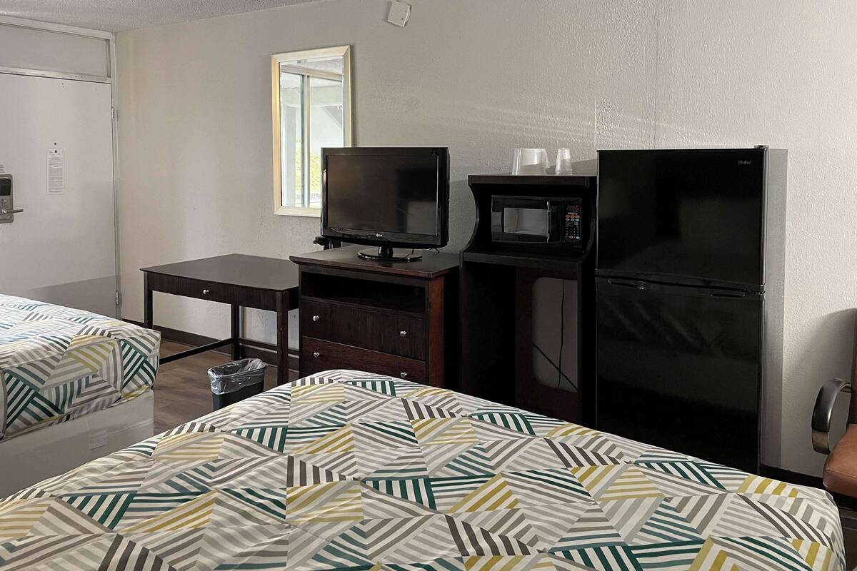Ein Hotelzimmer mit einem Bett, einem Schreibtisch mit Fernseher, einer Mikrowelle und einem Kühlschrank.