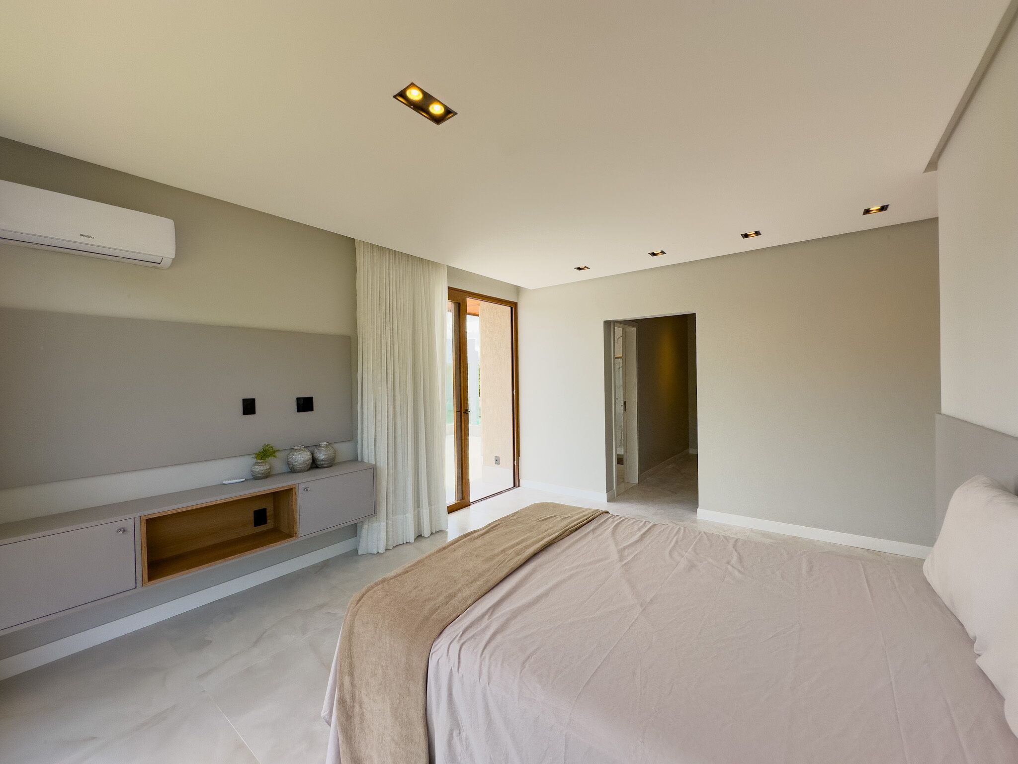 A modern bedroom with a large bed, a built-in wardrobe, and a ceiling-mounted air conditioner.