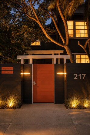 A building entrance with a large wooden door, a number '217' on the wall, and a sign for 'The Venice Beachwood rental management.'