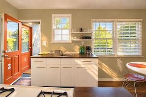 A modern kitchen with white cabinets, a wooden countertop, a built-in sink, and a window with blinds.