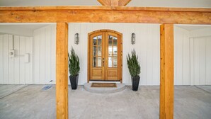 A wooden-framed entrance with a double door, potted plants, and a welcome mat.