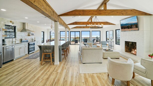 A spacious kitchen with wooden beams, a dining area with a large island, and a living room with a fireplace.