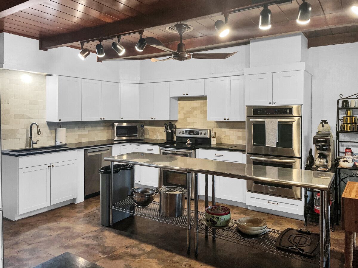 A modern kitchen with white cabinetry, stainless steel appliances, and a central island.