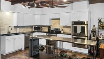 A modern kitchen with white cabinetry, stainless steel appliances, and a central island.