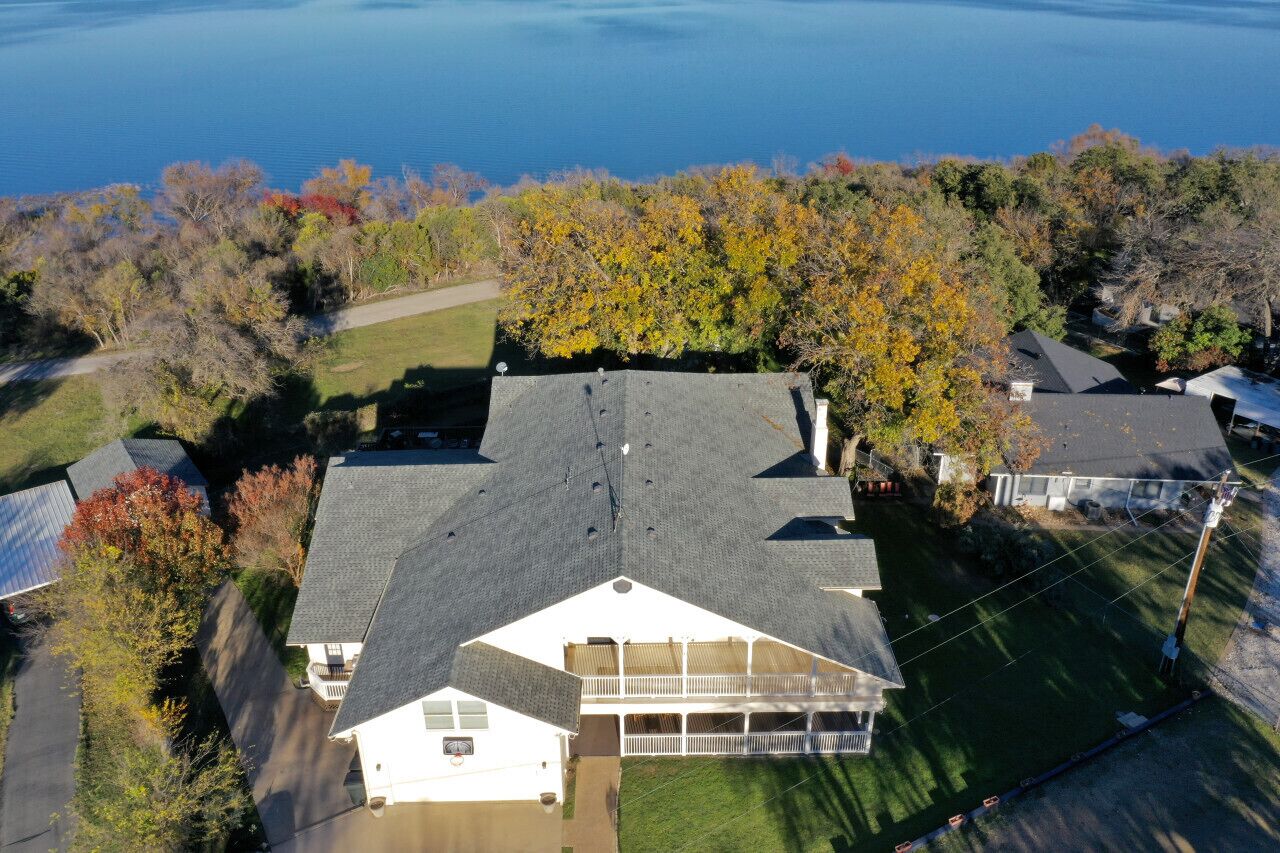 Un quartier résidentiel où se trouve une maison dotée d’un grand garage, d’un porche abrité et offrant une vue sur un lac.