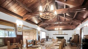 Un coin repas avec une table en bois dressée pour le repas, des chaises en bois et un lustre.