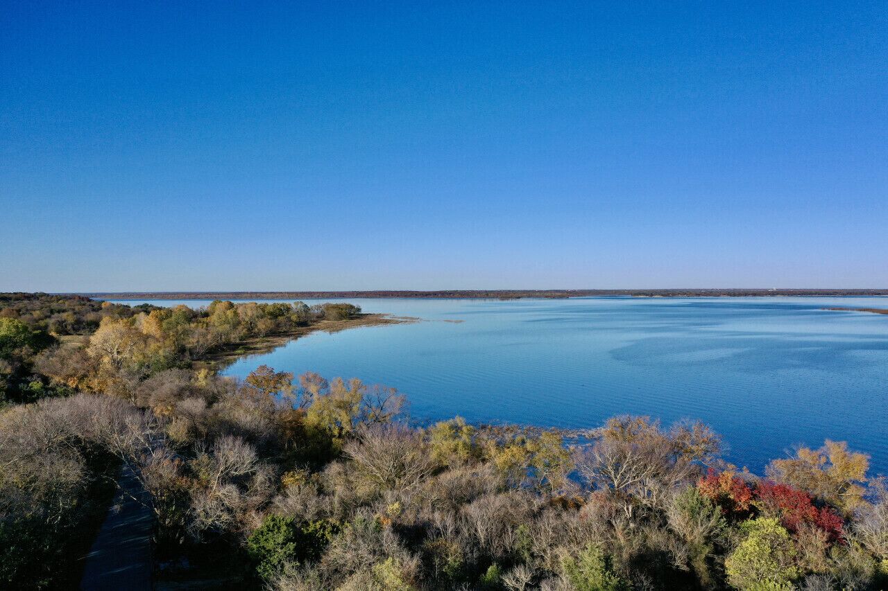 A calm lake surrounded by dense forest with autumn foliage.