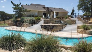 Un espace piscine agrémenté d’un escalier en pierre menant à un bâtiment, le tout entouré d’un aménagement paysager et d’une clôture.