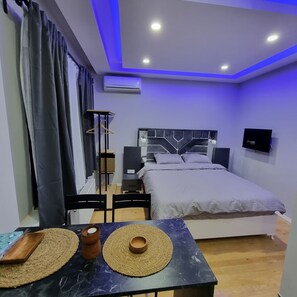 A modern bedroom with a bed, bedside tables, a TV, and a table with decorative mats. - Amur 205 (Istanbul)
