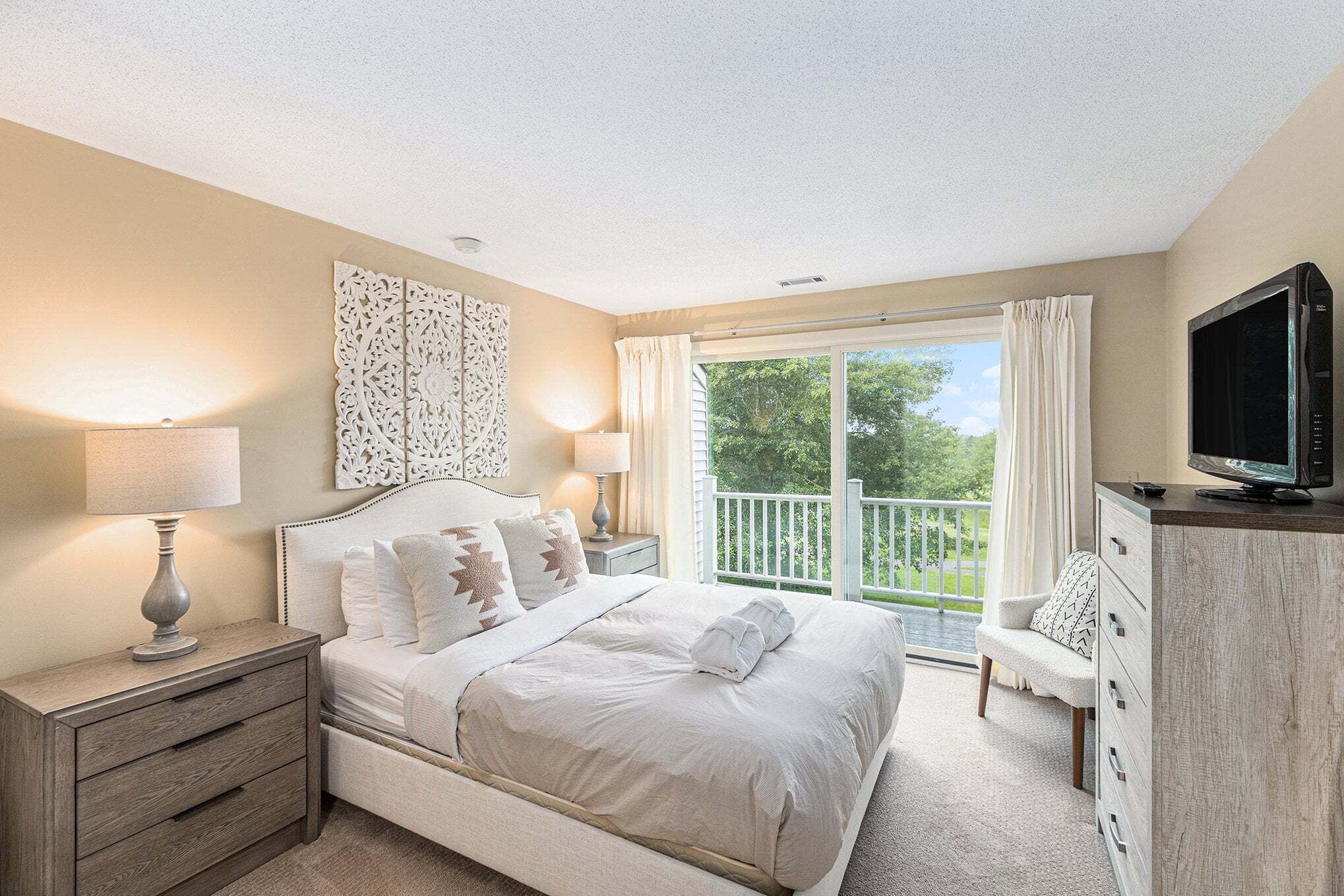 A bedroom with a bed, bedside tables, a TV, a balcony with a view.