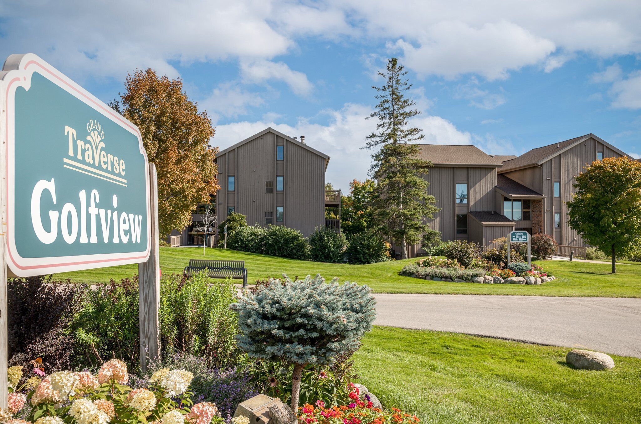 A sign for Grand Traverse Golfview, a modern building with multiple windows and a well-maintained lawn.