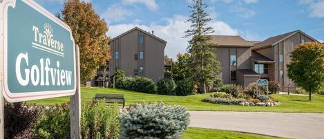 A sign for Grand Traverse Golfview, a modern building with multiple windows and a well-maintained lawn.