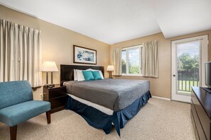A bedroom with a bed, a chair, a nightstand, a lamp, a television, and a window. - 2BDR Loft Suite Golf Course Condo 5549 (Williamsburg)