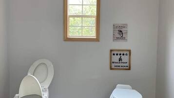 Ein Badezimmer mit zwei Toiletten, einem Fenster und zwei Schildern an der Wand.