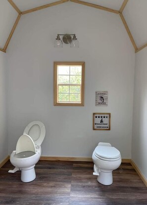 Ein Badezimmer mit zwei Toiletten, einem Fenster und zwei Schildern an der Wand.