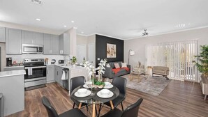 A modern kitchen with grey cabinets, a dining area with a round table, and a living room with a sofa and a plant. - Stylish 2BR Scottsdale, Pet-friendly, Sunrise Peak (Scottsdale)