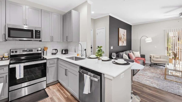 A modern kitchen with stainless steel appliances, a central island, and a dining area with a sofa and coffee table. - Stylish 2BR Scottsdale, Pet-friendly, Sunrise Peak (Scottsdale)