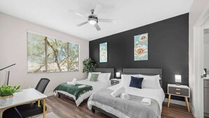 A modern bedroom with two beds, a desk, and a ceiling fan. - Stylish 2BR Scottsdale, Pet-friendly, Sunrise Peak (Scottsdale)