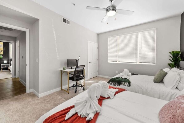 A modern hotel room with a bed, a desk, a chair, and a ceiling fan. - Relaxing 2-Bedroom, Pet-Friendly Near Sunrise Peak (Scottsdale)