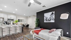 A modern apartment with a kitchen, dining area, and a bedroom with a large bed and a ceiling fan. - Chic 1-Bedroom Pet-Friendly, Near Sunrise Peak (Scottsdale)
