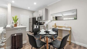 A modern kitchen with white cabinets, a microwave, and a dining area with a glass table and black chairs. - Chic 1-Bedroom Pet-Friendly, Near Sunrise Peak (Scottsdale)