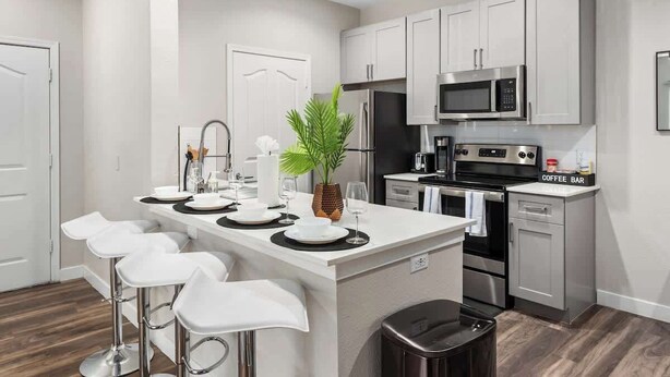A modern kitchen with white cabinetry, stainless steel appliances, and a central island with bar stools. - Chic 1-Bedroom Pet-Friendly, Near Sunrise Peak (Scottsdale)