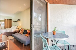 A room with a bed, a sofa, a table with chairs, and a sliding glass door leading to an outdoor area with a table and chairs. - Cozy, modern Pearl St. condo. Ideal location! (Boulder)