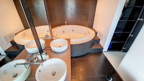 Un baño con dos tinas redondas, tres lavamanos y un espejo grande.