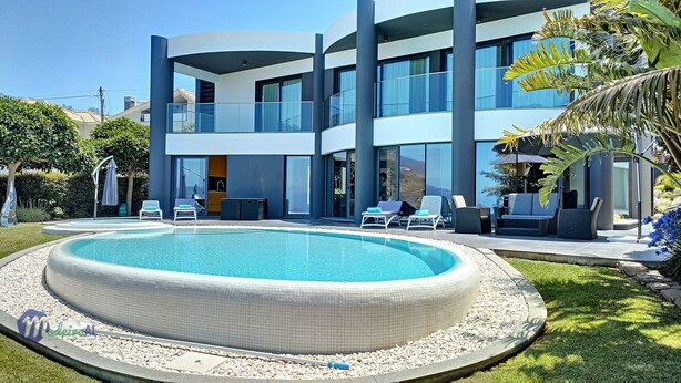A modern two-story building with a swimming pool, lounge chairs, and a patio area. - Villa Bonsai (Calheta)