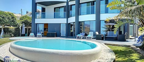 Alberca al aire libre, sombrillas en la alberca y camastros