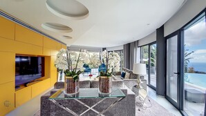 A modern living room with a large TV, two orchid vases, and a glass coffee table. - Villa Bonsai (Calheta)
