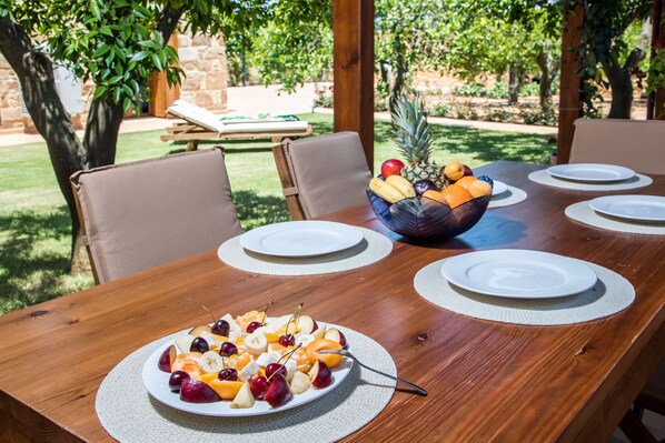 A wooden dining table with a fruit platter and a bowl of fruit.
