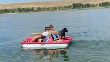 Una piccola imbarcazione gonfiabile rossa con tre persone e un cane su un lago calmo.