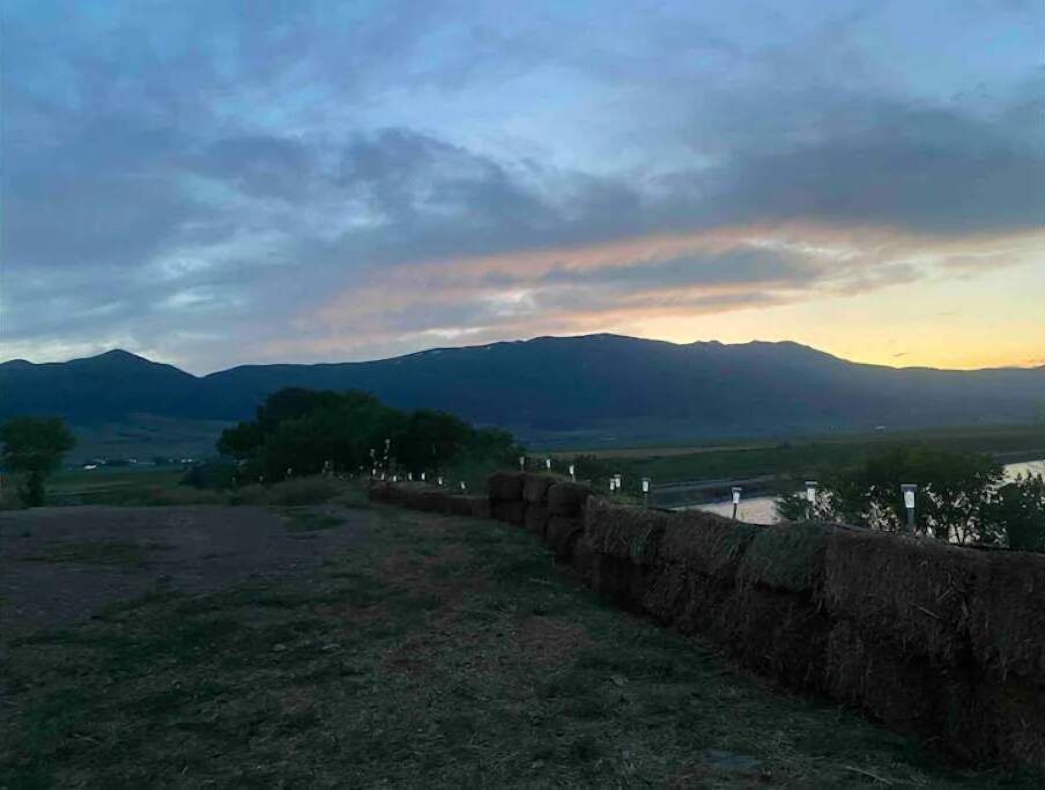 Un paysage rural avec des montagnes, une rivière et un mur de pierres.