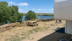 A campsite with picnic tables and a lake view. - Queen and twin bed Trailer on private beach, Hammocks, tiki torches, fishing (Clifton)
